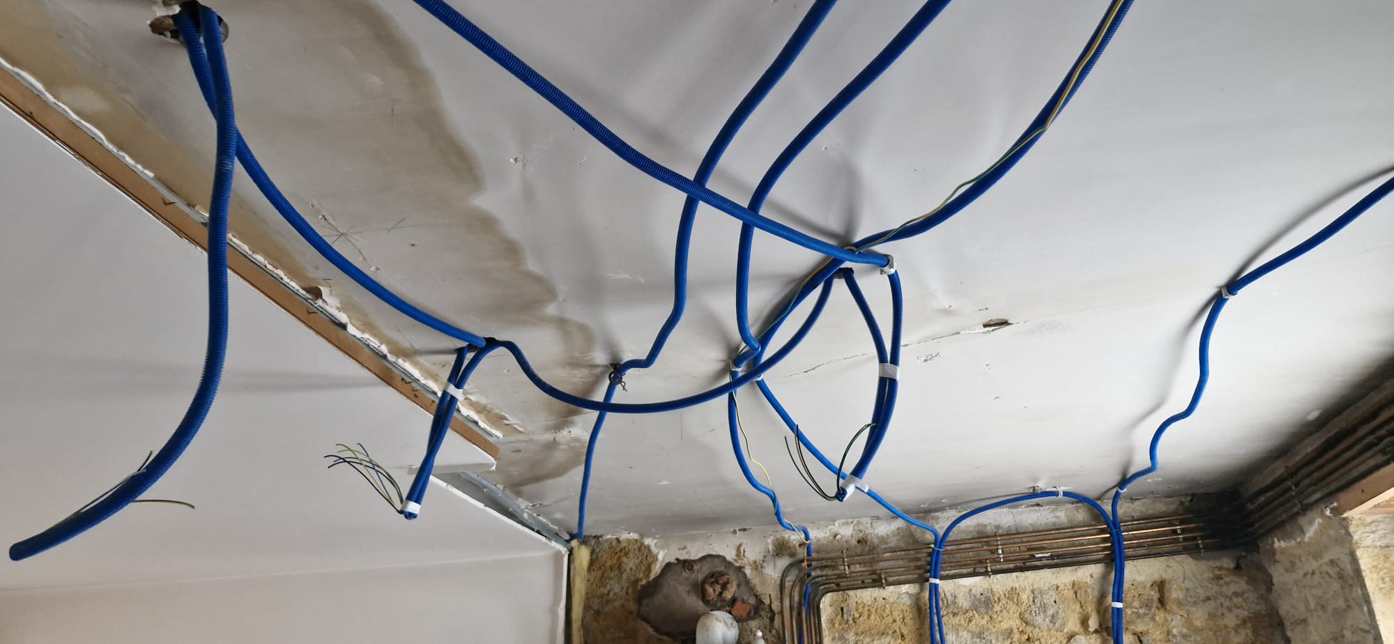 Passage des gaines électriques bleues au plafond avant pose du placo