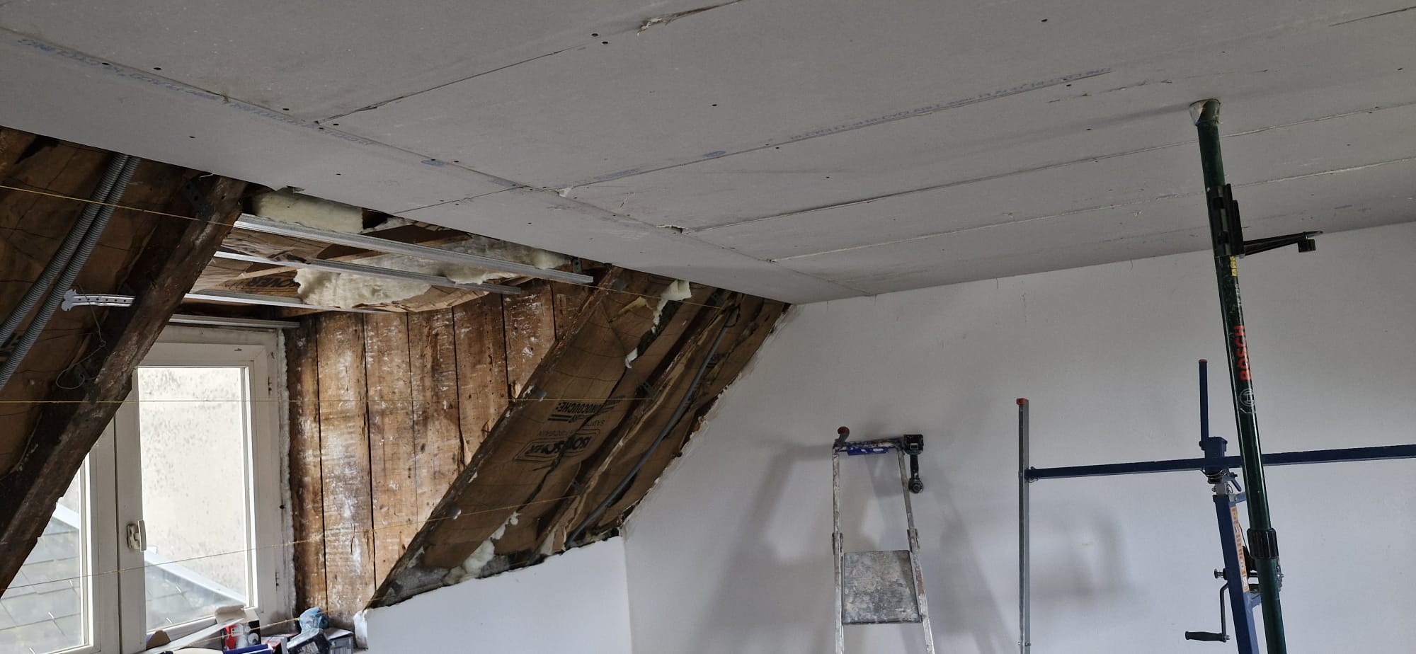 Pose de plaques de placo au plafond de combles en cours d'aménagement